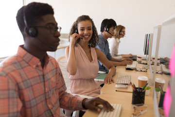 Executives working on personal computer while talking on headset in office