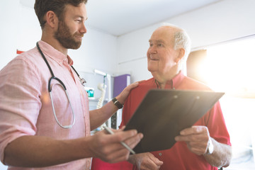 Obraz premium Male doctor showing medical report to senior patient
