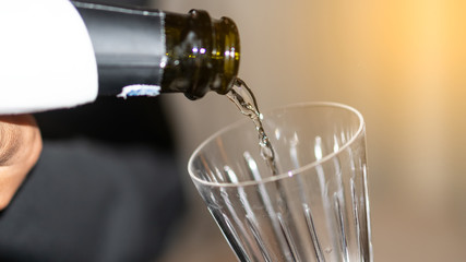 Pour the wine into the glass, the background is blurred and the orange light