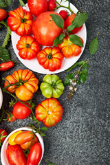 Mix of tomatoes background. Beautiful juicy organic red tomatoes on black  table background. Clean eating concept. Copy space, flat lay..