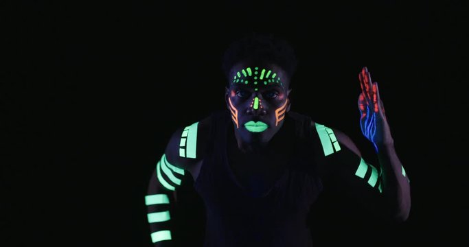 Studio, slow motion, close-up of a neon-painter dancing 