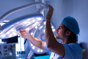 Male surgeon fixing surgical light at hospital