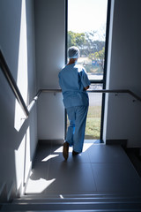 Fototapeta premium Female surgeon looking through the window in the hospital stairs