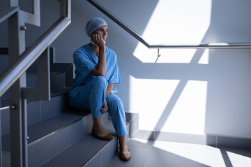 Female surgeon sitting on stair case in hospital