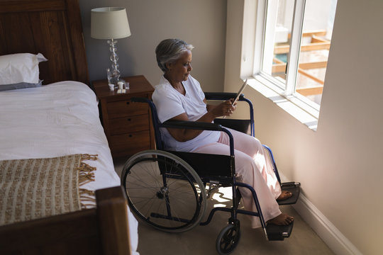 Disabled senior woman using digital tablet in bedroom