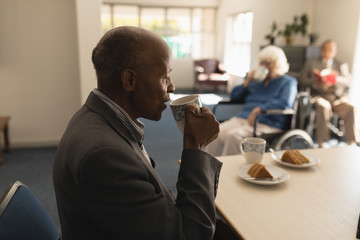 Side view of senior man drinking coffee on dining table