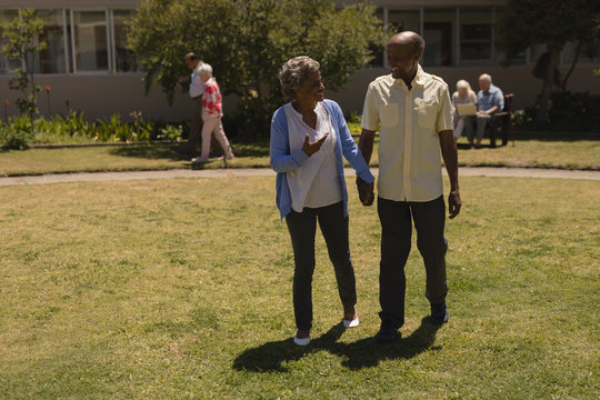 Front view of senior couple holding hands and interacting with each other in garden 