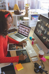 Female graphic designer using graphic tablet at desk 