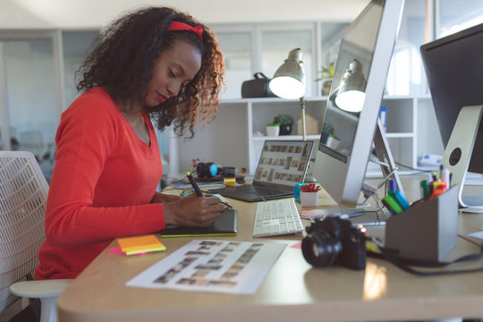 Female graphic designer using graphic tablet at desk 