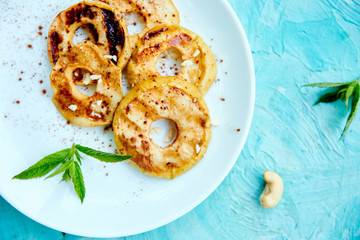 Grilled apples with cinamon on white plate on blue background. Grilled dessert. Barbecue fruit. Copy space. Healthy food. Vegan food.