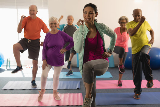 Front view of female trainer assisting senior people in fitness studio
