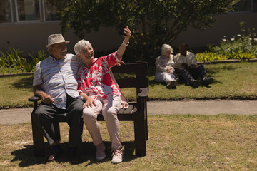 Front view of senior couple taking selfie with mobile phone in garden