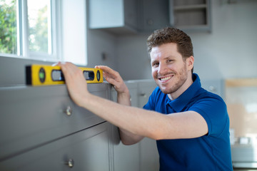 Portrait Of Carpenter Installing Luxury Modern Fitted Kitchen