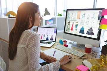 Female fashion designer working on computer at desk  - obrazy, fototapety, plakaty