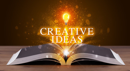 CREATIVE IDEAS inscription coming out from an open book, educational concept