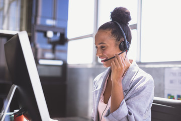 Businesswoman talking on headset while working on computer at desk 