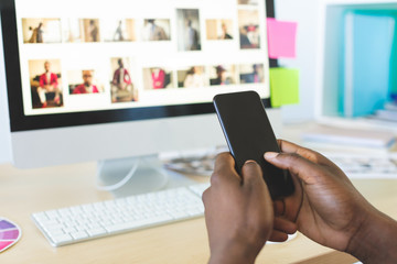 Graphic designer using mobile phone at desk