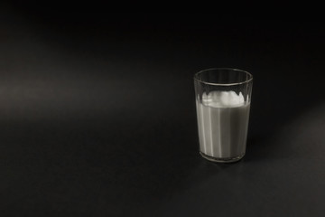 a glass of milk is placed on a black background
