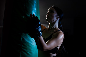 Young female boxer punching a bag on a sports training in a gym.