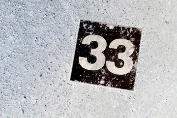 Number 33 black plate on white wall background - obrazy, fototapety, plakaty