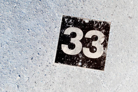 Number 33 Black Plate On White Wall Background