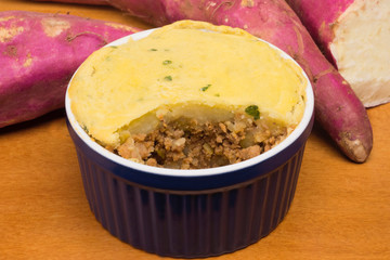 Cut diet version of shepherd's pie made of sweet potato and stuffed with ground beef in wood background