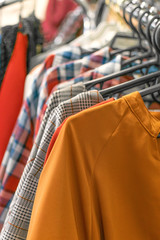 Colorful trend women dresses, pants  on hangers in retail shop, store. Fashion and shopping concept. Fall fashion trends