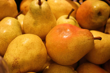 Yellow shiny ripe pears in yellow market place light