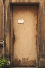 Old aged weathered brown door with piece of paper