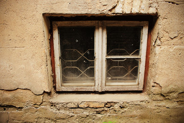 Small dirty window in old gray plaster wall