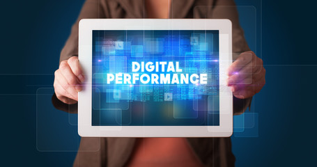 Young business person working on tablet and shows the inscription: DIGITAL PERFORMANCE
