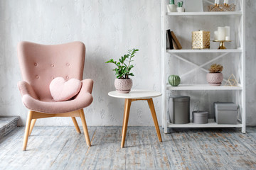 Stylish pink armchair with heart shaped pillow in a bright minimalist interior - obrazy, fototapety, plakaty