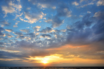 Naklejka na ściany i meble Seashore sky orange and blue tones clouds and sea waves beautiful nature bright sunset