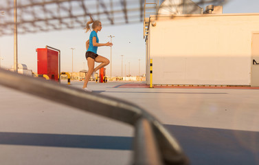 Young woman running on parking level in the city at sunset