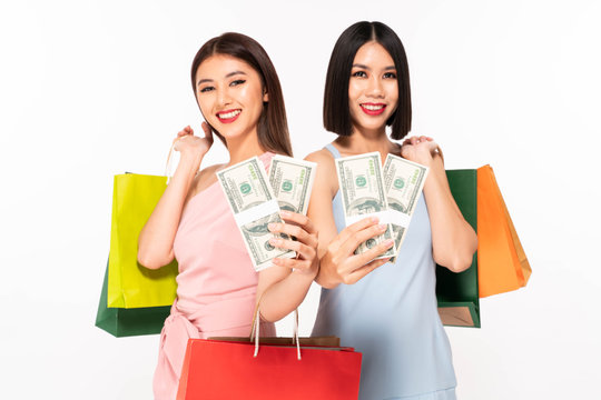 Close up excited happy young pretty women friends posing isolated over white background holding shopping bagt money