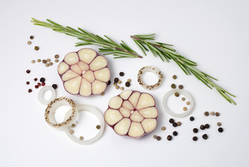 Fototapeta na wymiar Food background of onion rings, peppercorns, rosemary and garlic cloves, on white.