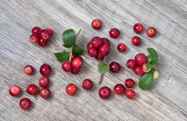 Red ripe lingonberry with leaves, on wooden background, top view.