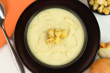 Onion soup with croutons in a black bowl seen from above