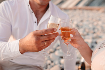 Man and woman clanging wine glasses with champagne at sunset