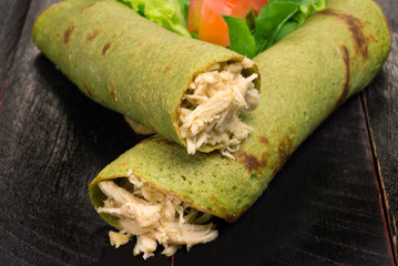 Spinach pancake stuffed with chicken breast and salad in black background