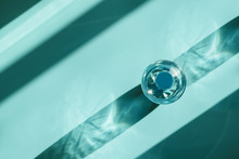 Bottle of water with reflecting shadows on blue background.  Healthy food concept. Top view. Copy space