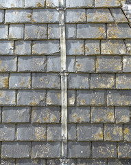 background of slate roof tiles on an old roof with a lightening conductor in the middle