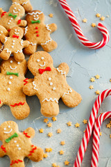 Biscuits gingerbread man cookies and candy cane on light blue background top view close-up.Festive food.Christmas and New Year traditions concept.Vertical orientation