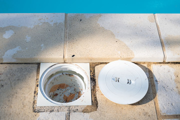 A pool skimmer basket with the lid off and leaves removed