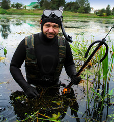 Spearfishing. A man in a wetsuit with a fish caught on the waterfront. 