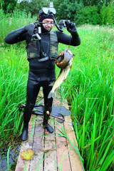 Spearfishing. A man in a wetsuit with a fish caught on the waterfront. 