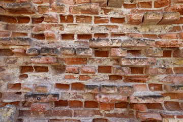 Very old and worn brick wall with red bricks