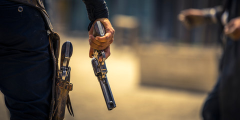 Man holding his six-shooter ready for a gunfight, Western movie set - obrazy, fototapety, plakaty