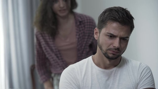 Young curly woman swearing and screaming to her curly annoying boyfriend in the living room becouse of misunderstanding