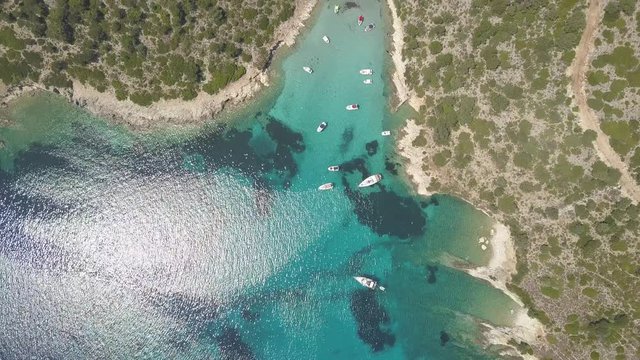 An approaching drone shot towards sea beach and mountains. Tourist boats ride in sea water. Kastos island, Greece